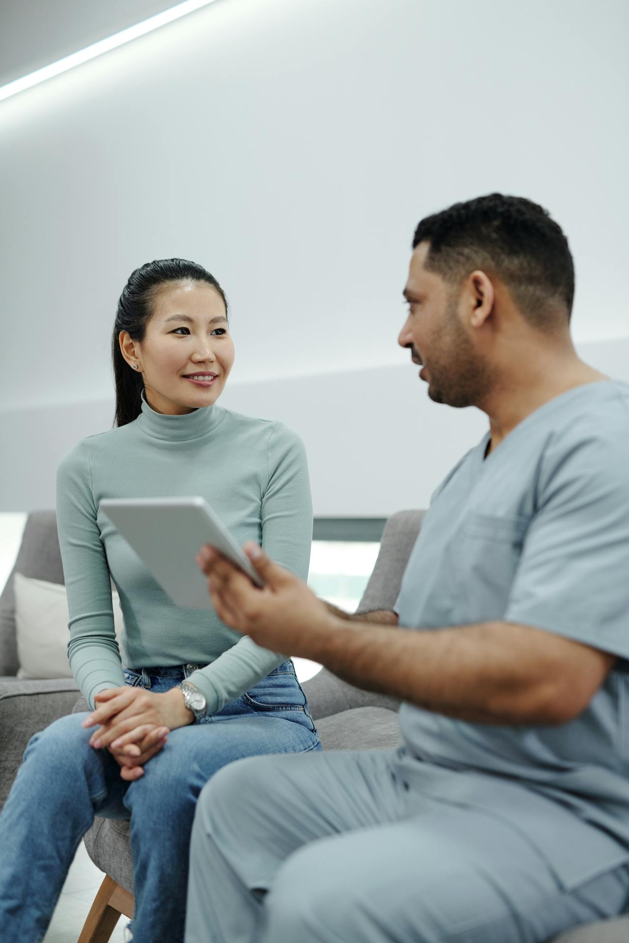 A professional medical concierge listening intently to a patient in a bright, modern clinic.